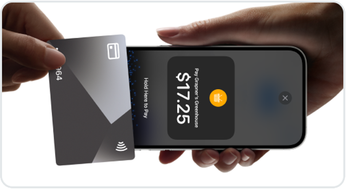 Credit card held over a mobile device for contactless payment.
